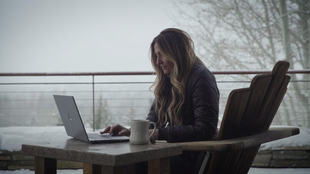Jody Macdonald sitting outside at a table with her HP laptop, fog in the background