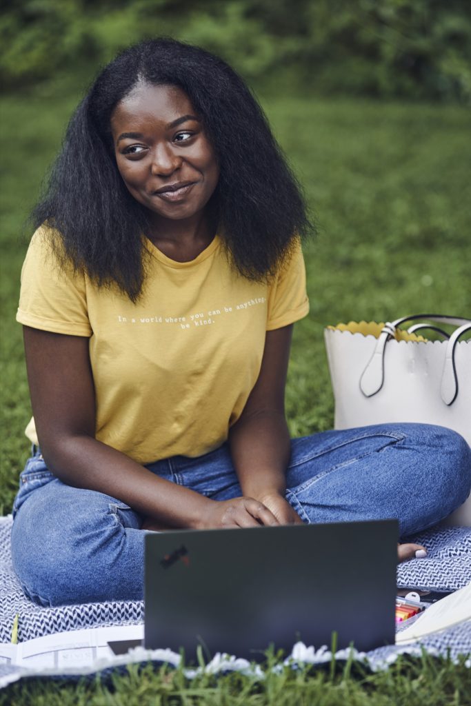 Women sitting in front of a laptop on a grassy field Women sitting in front of a laptop on a grassy field