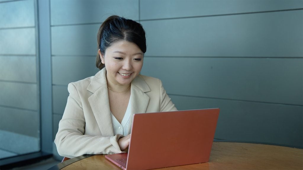 Woman smiles while looking at her laptop