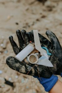 Gloved hand holding litter left on beach