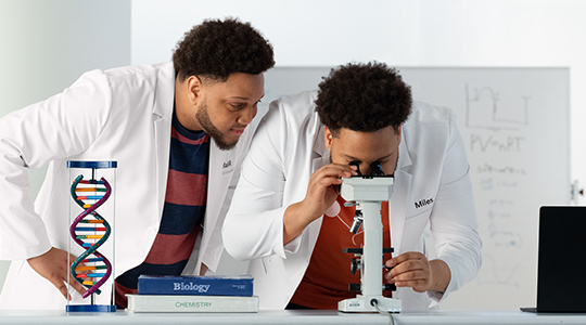 Two men in lab coats peering through a microscope