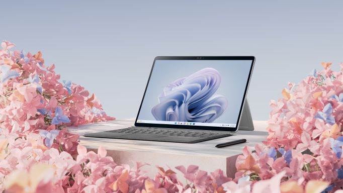 Surface Pro 9 open and on a white table surrounded by pastel flowers